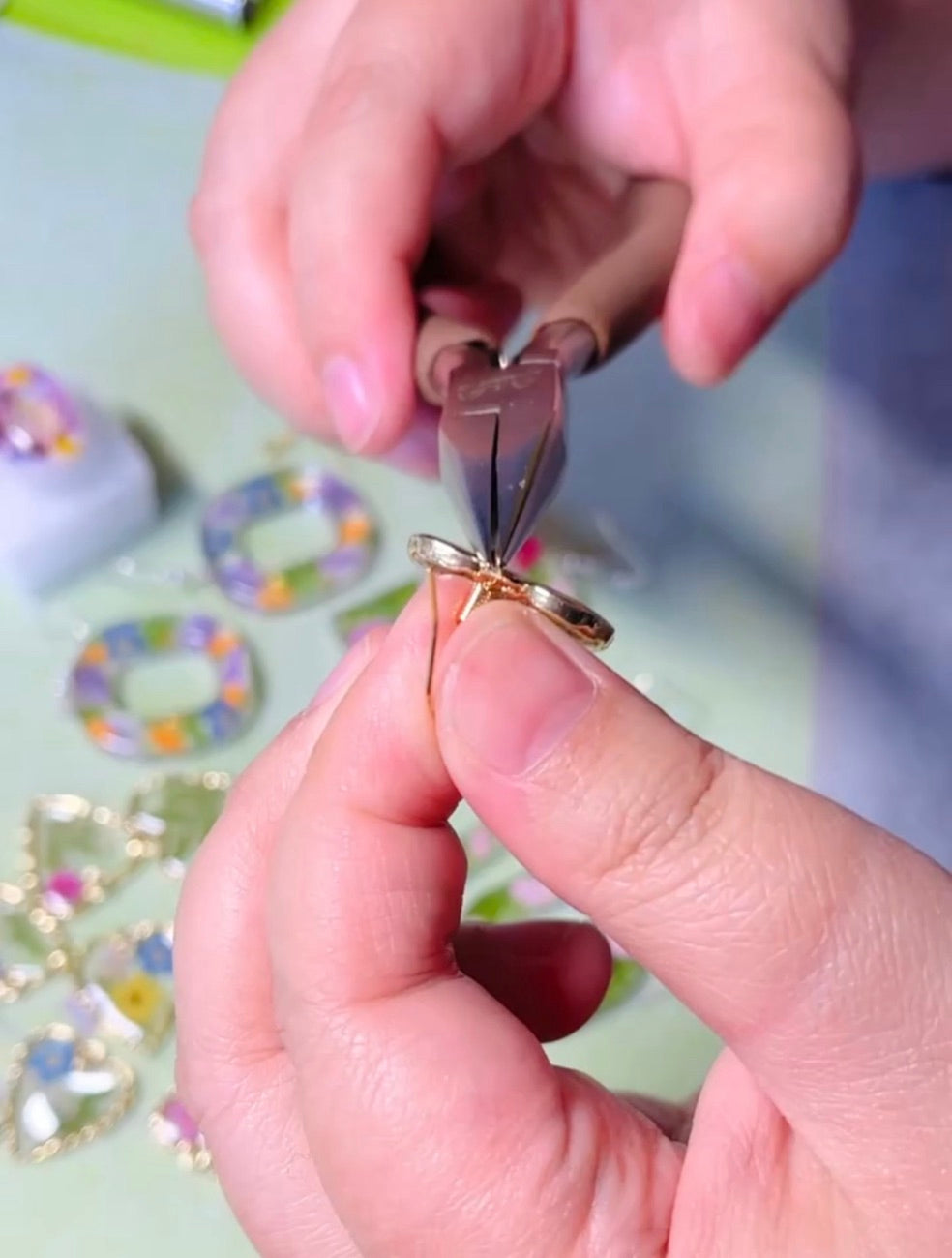 Hands assembling a handmade botanical jewelry piece in the studio